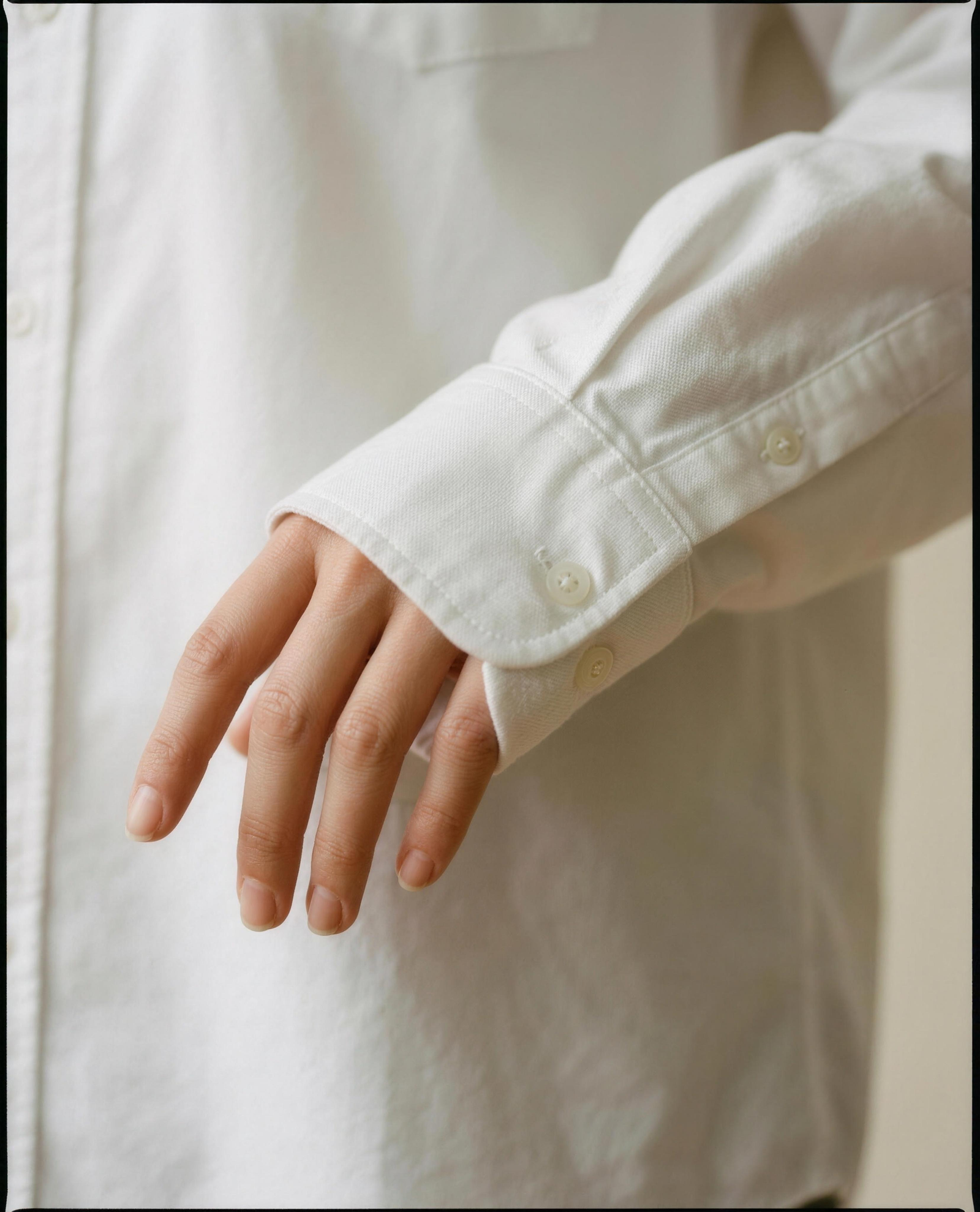 Close-up of the buttoned barrel cuff and sleeve placket on the bride's cotton Oxford shirt